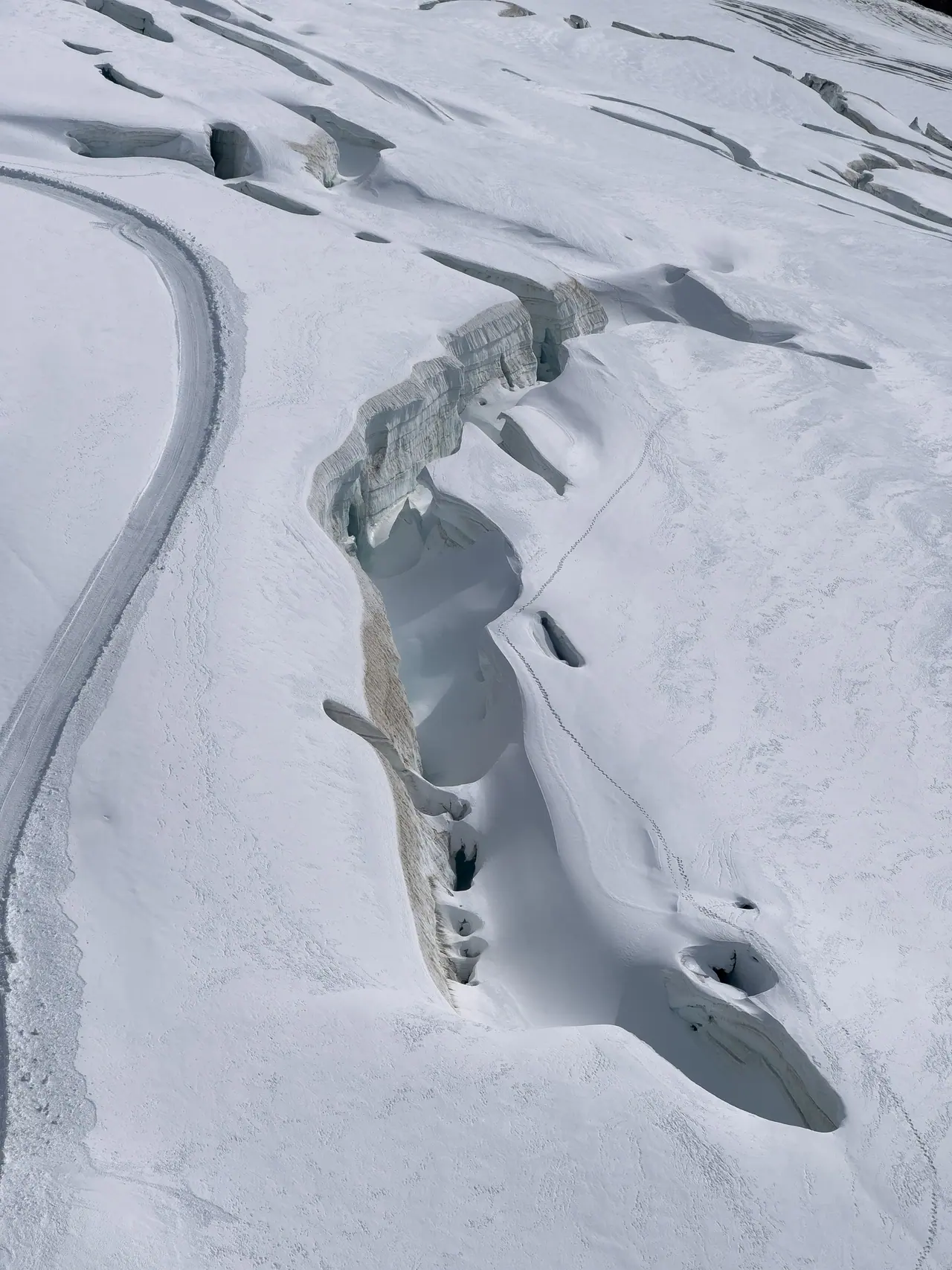 A blue crevasse cutting through snow and ice